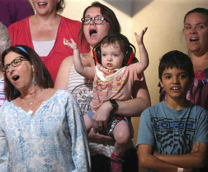 Kristina Lockwood holds her 1-1/2 year old daughter Elise as SingStark! performs classic Beatles tunes at the Canton Brewing Company Speakeasy.  (Scott Heckel / The Canton Repository)